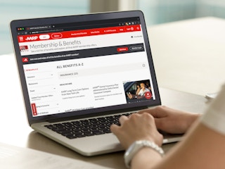 A person using a laptop displaying the AARP website's Member Benefits