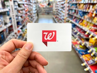 A person holding a Walgreens gift card inside Walgreens.