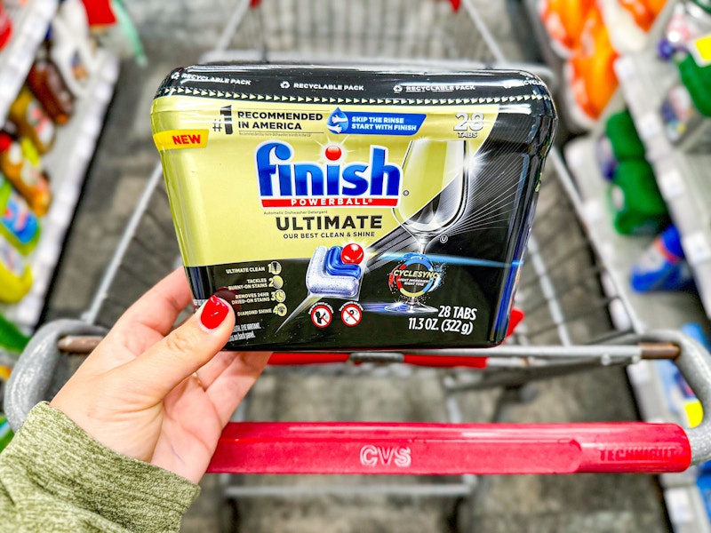 person holding finish dishwasher tabs over a cart