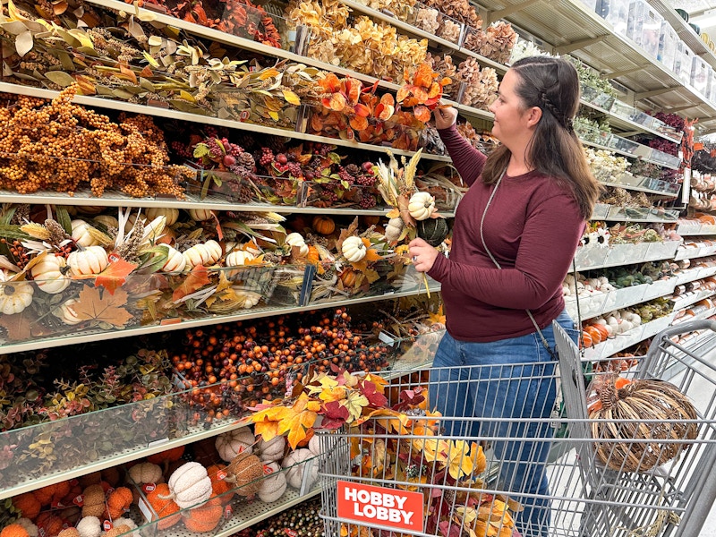 a woman grabbing fall silk flowers in store at hobby lobby