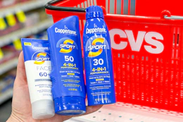hand holding coppertone sunscreens in front of a cvs shopping basket