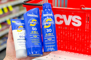 hand holding coppertone sunscreens in front of a cvs shopping basket