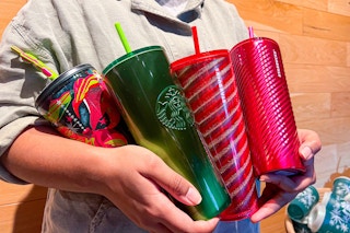 someone holding some starbucks holiday cups