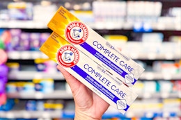 hand holding two boxes of Arm & Hammer Complete Care toothpaste