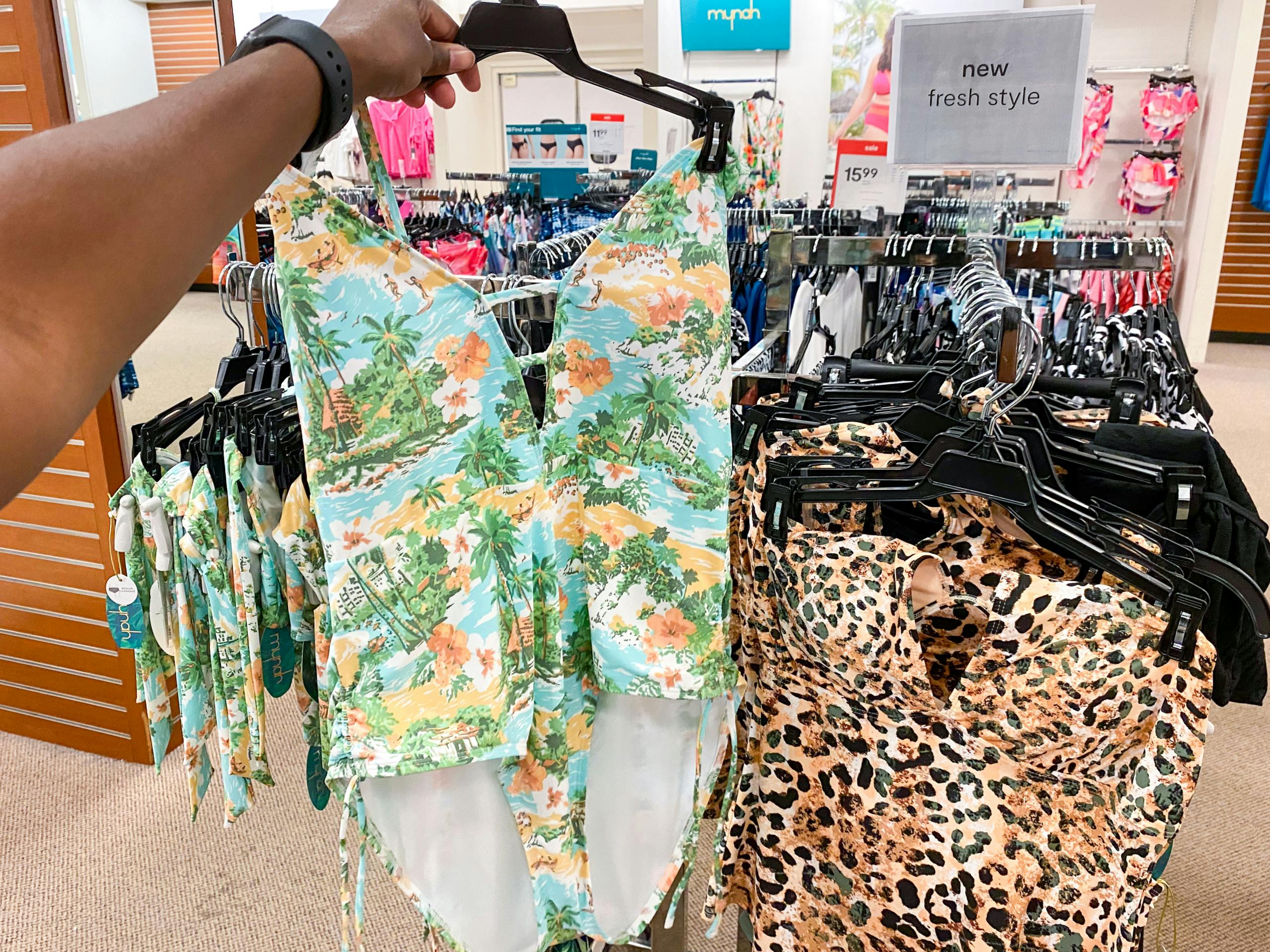 someone holding up a swimsuit in the swimwear section in jcpenney