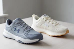 two different pairs of Under Armour Shoes for adults on a table 
