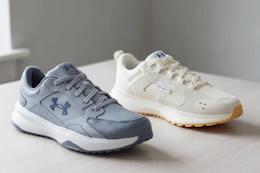 two different pairs of Under Armour Shoes for adults on a table 