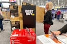 a woman pulling a tv off a sales rack inside best buy during black friday
