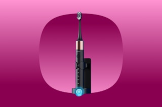 A rechargeable black sonic electric toothbrush sits upright in a wall holder