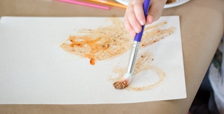 a child painting a piece of paper with spices