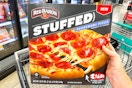 hand holding a red baron stuffed crust pizza