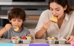 a kid and a mom eating food out of stainless steel trays