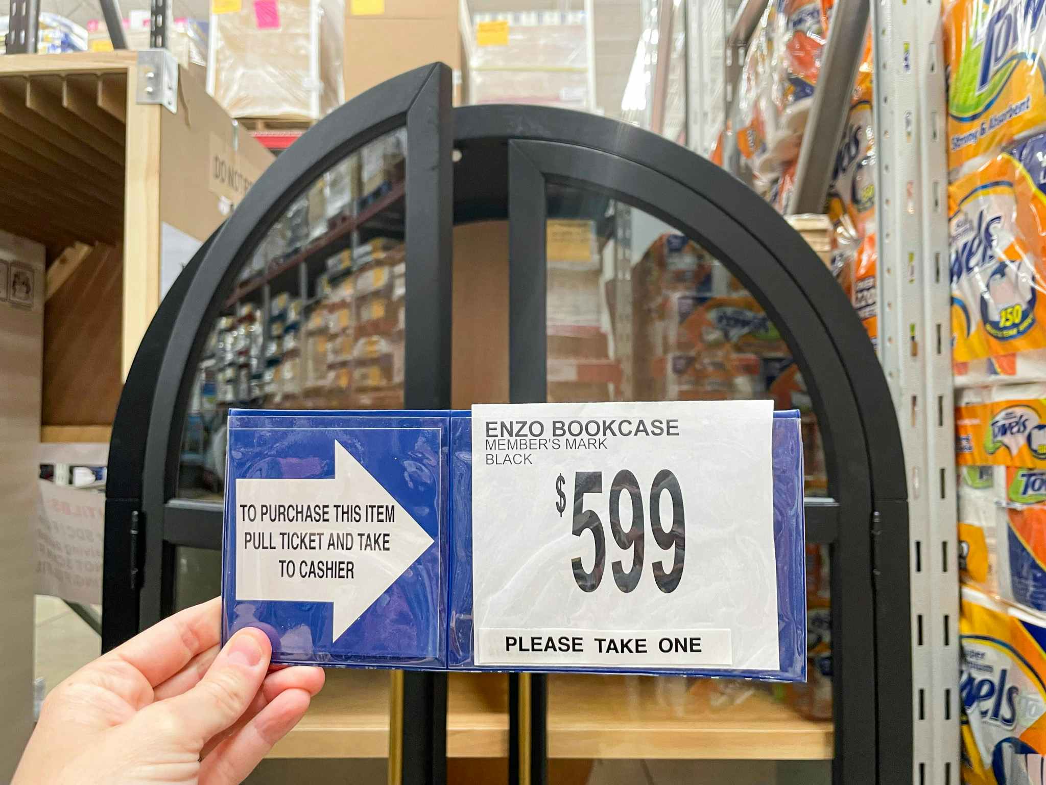person holding a $599 price sign in front of a bookcase