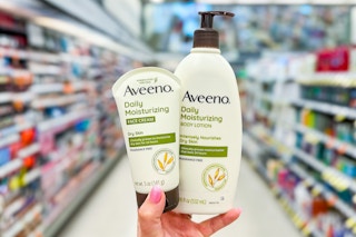 hand holding aveeno lotion bottle and aveeno face cream bottle in a store aisle