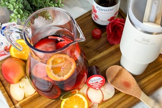 a pitcher of sangra on a counter next to fruit and splenda fruit punch  and a stanley cup 
