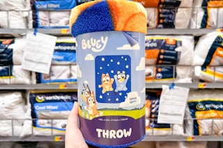 Bluey Throw Blanket held up in front of pillows at Walmart