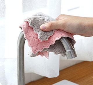 a person wiping a sink faucet with a cloth