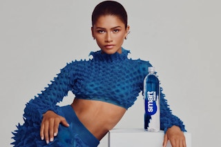 Zendaya wears a blue textured crop top and poses next to a bottle of Smartwater.