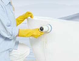 a person using an electric scrubber on a bathtub 