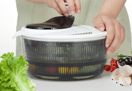 a person using a salad spinner with veggies inside