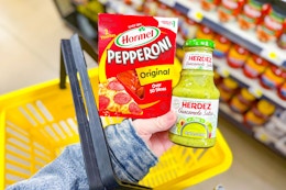hand holding hormel and herdez above yellow shopping basket