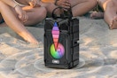Dnil Portable Speaker on a beach next to people.