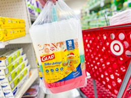 hand holding a glad holiday container set in front of a parked target cart