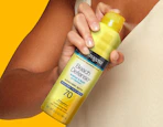 a person holding a yellow can of sunscreen