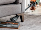 a person vacuuming under a couch