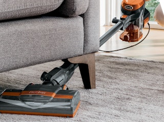 a person vacuuming under a couch