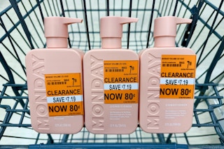 three bottles of monday haircare conditioner with orange clearance tags in a shopping cart