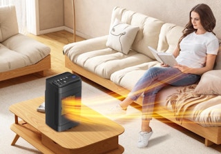 a space heater on a coffee table next to a woman reading on a couch