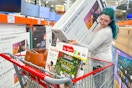 a woman putting a large tv in a costco cart in store during black friday shopping deals