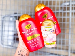 hand holding bond repair shampoo, conditioner, and coconut oil hair serum