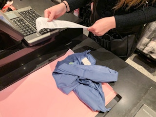 Female employee looking at a receipt to return an item at the register.