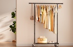 a clothing rack with clothes against the wall