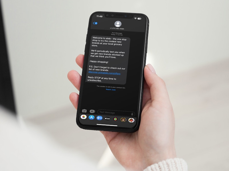 Someone holding a phone showing a text message from subscribing to Aisle text alerts