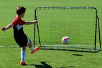 child kicking ball into net