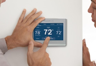 a couple of people using the Honeywell Home Smart Thermostat