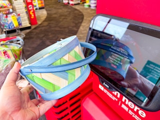 person holding a small basket by a price scanner