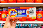 hand holding tide washing machine cleaner in front of target shelves