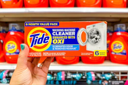 hand holding tide washing machine cleaner in front of target shelves