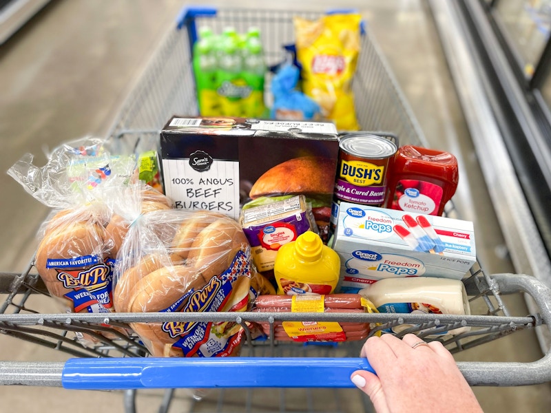 Someone pushing a cart filled with grilling essentials at Walmart