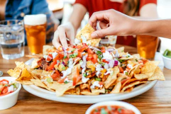 a group of friends eating nachos at a mexican restaurant