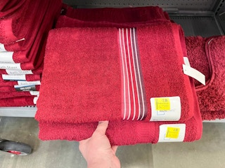hand holding mainstays bath towel and sheet on walmart shelf