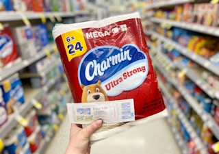 hand holding charmin toilet paper and a walgreens catalina coupon in a store aisle