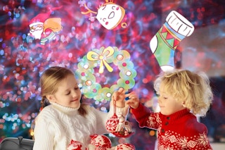 two kids opening presents in front of Christmas decorations