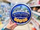 a hand holding a blue tin of cookies in a store aisle