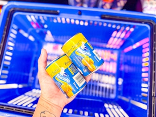 hand holding two tubes of pillsbury grands biscuits over walmart hand cart