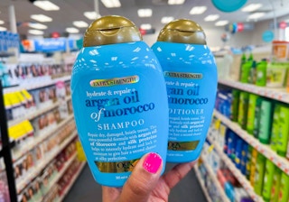 a hand holding two blue bottles of shampoo in a store